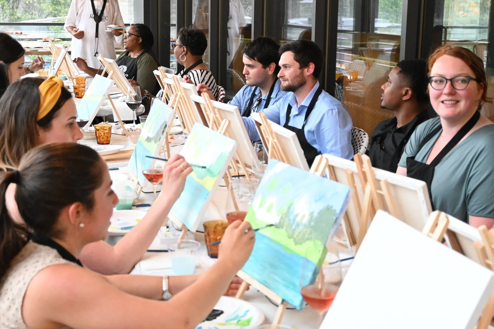 Coworkers painting at tabletop easels during a private paint and sip