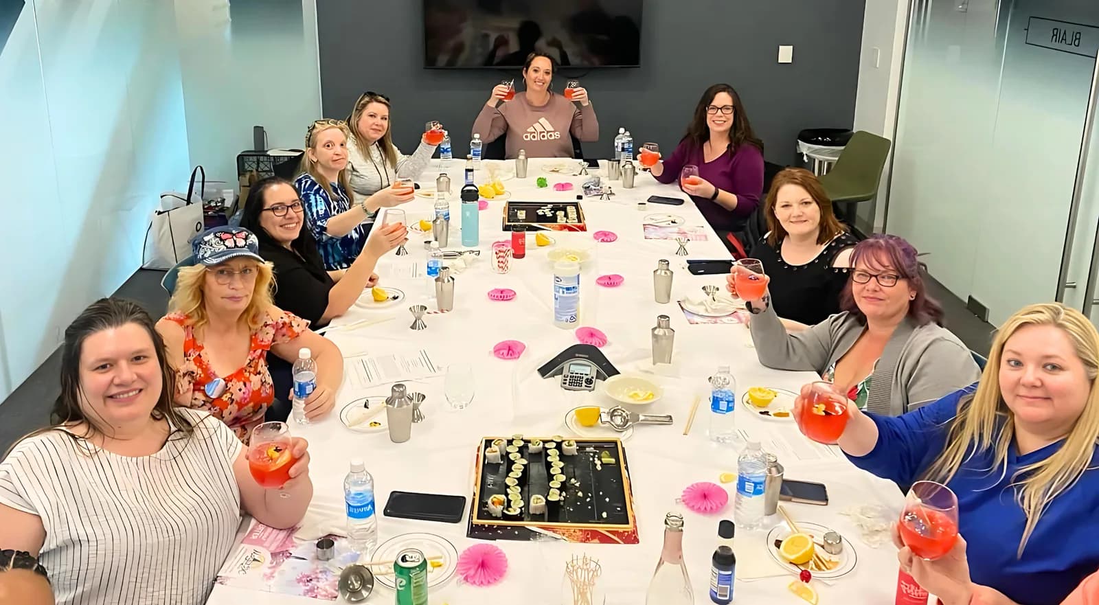 Team around a conference table with cocktails during an in-office mixology class